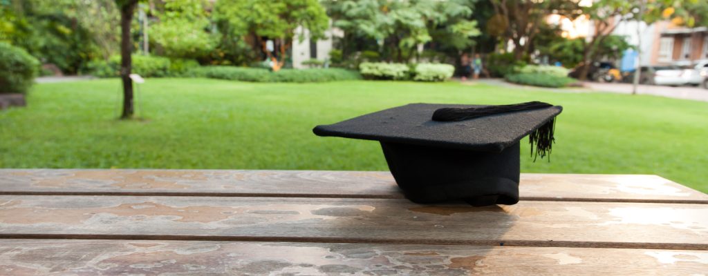 Graduation hat on vintage table with green nature background